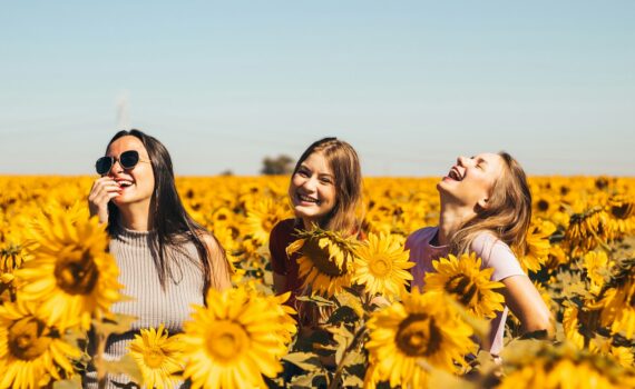 woman in white and black striped shirt standing on yellow sunflower field during daytime