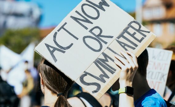a woman holding a sign that says act now or summer