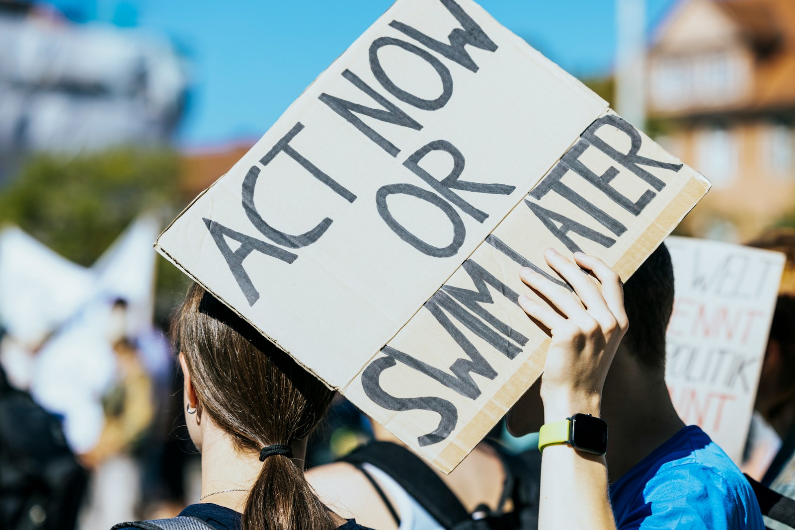 a woman holding a sign that says act now or summer