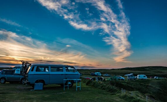 A scenic sunset view of Volkswagen campervans parked in Durness, Scotland.